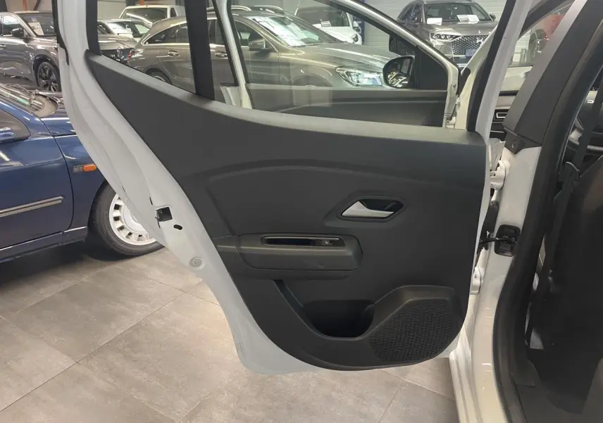 Vue intérieure de la porte arrière gauche blanche d'une Dacia Sandero 2024 avec habillage noir et poignée argentée.