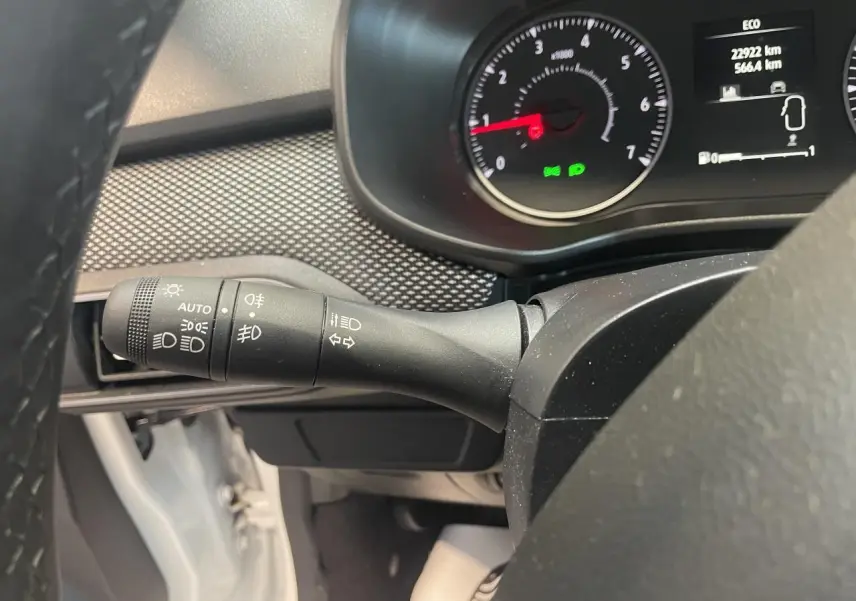 Vue rapprochée du commodo d’éclairage noir à gauche du volant dans une Dacia Sandero blanche 2024.