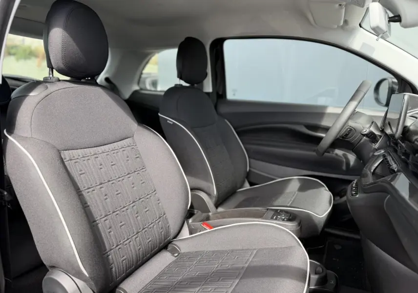 Vue intérieure des sièges avant en tissu noir avec surpiqûres blanches de la Fiat 500 électrique 2024, côté droit.
