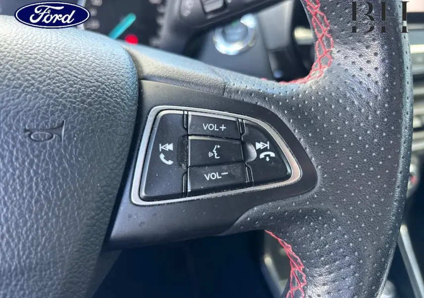 Gros plan sur les commandes de volume et téléphone au volant cuir perforé avec surpiqûres rouges du Ford EcoSport 2018.