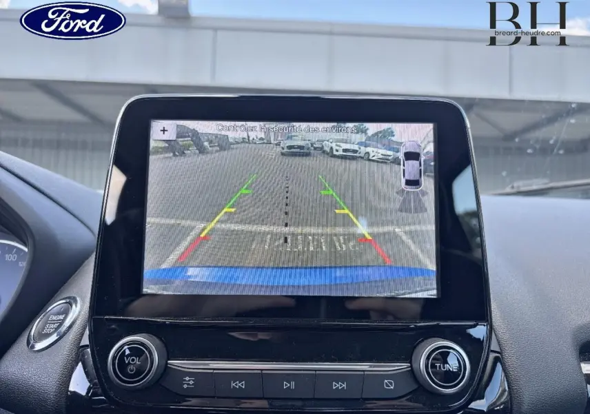 Écran tactile intérieur montrant la caméra de recul d'un Ford EcoSport bleu Lightning, avec commandes autour.