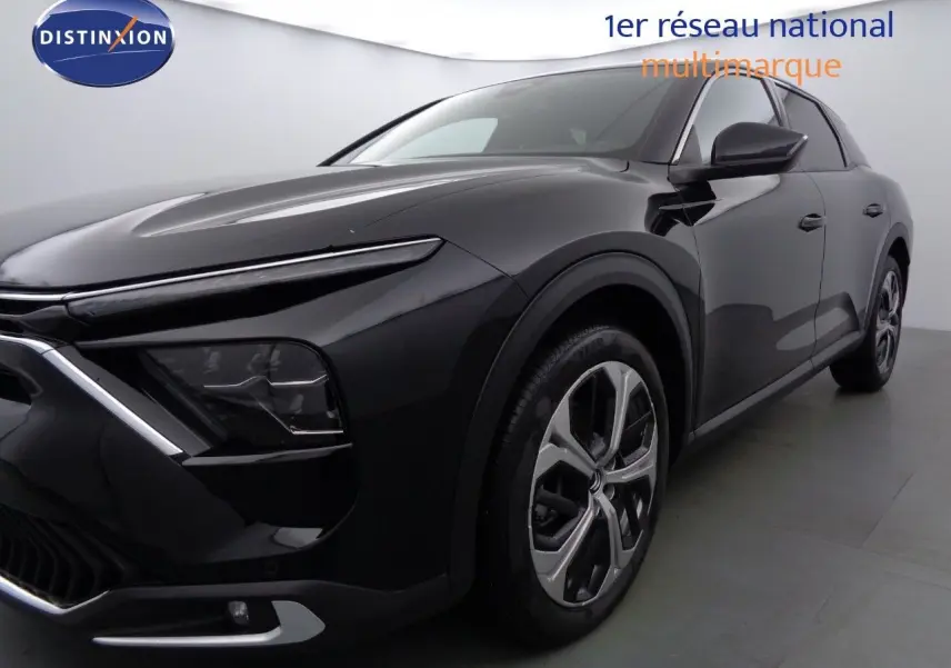 Gros plan sur la roue avant gauche de la Citroën C5 X noire métal, mettant en valeur la jante bi-ton au design moderne.