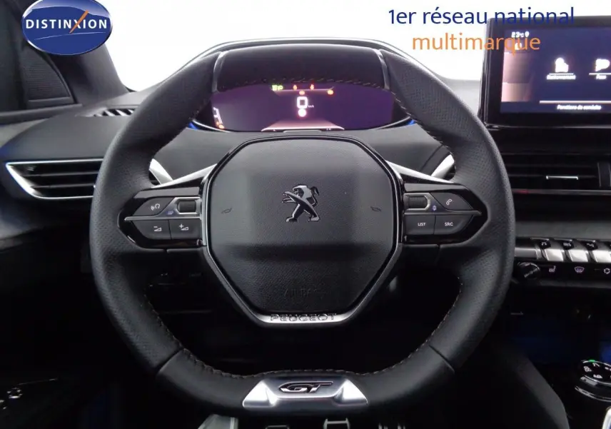 Vue rapprochée du volant cuir noir avec logo Peugeot et badge GT du Peugeot 3008 2023, tableau de bord en arrière-plan.