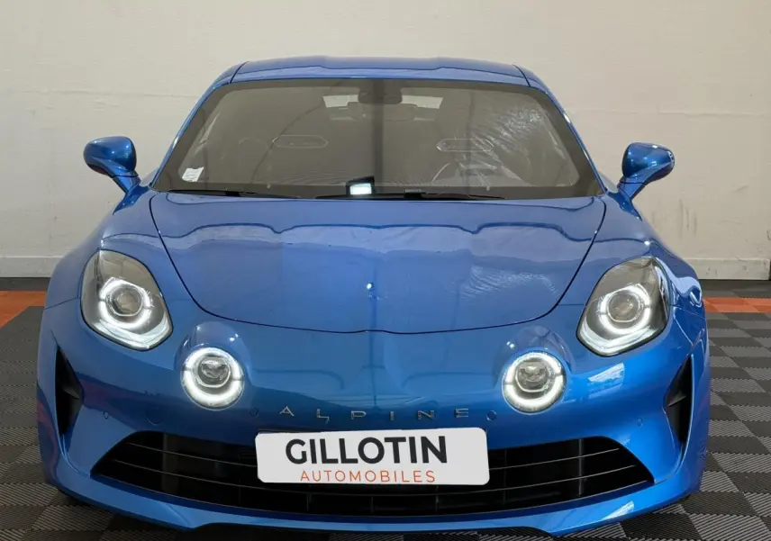 Vue frontale de l'Alpine A110 Légende 2019 en bleu, avec ses phares LED ronds caractéristiques allumés.