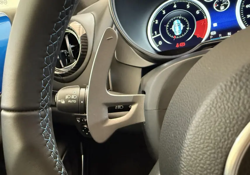 Gros plan sur le volant cuir noir avec surpiqûres bleues et le tableau de bord numérique de l'Alpine A110 Legende 2019.