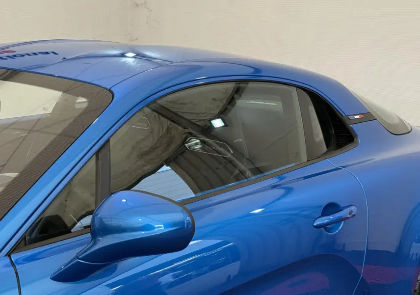 Vue côté gauche rapprochée de l'ALPINE A110 Legende bleu brillant avec rétroviseur et poignée de porte visibles.
