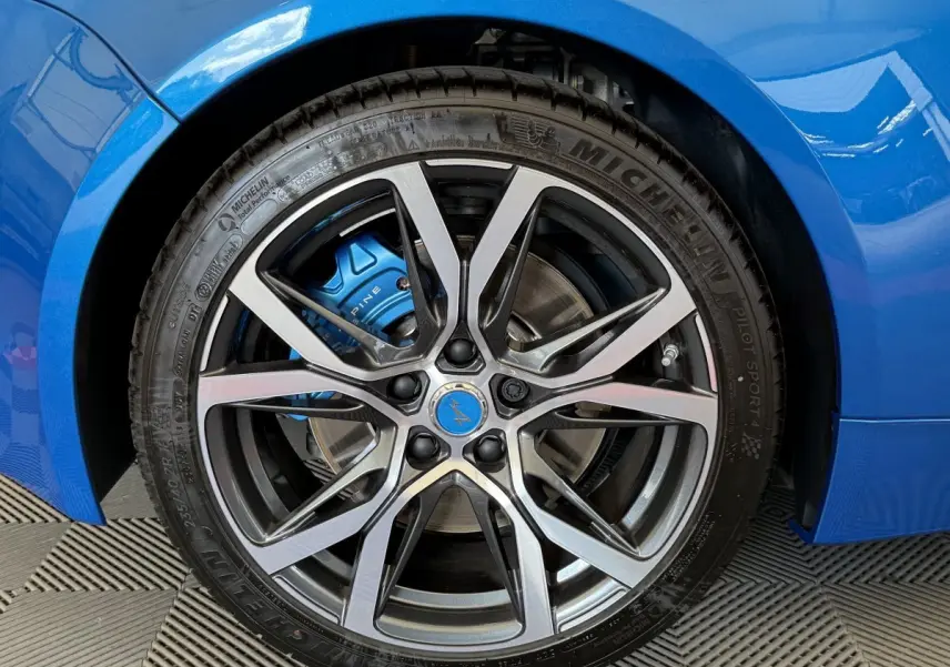 Gros plan sur la roue avant droite bleue d'une Alpine A110 Légende 2019 avec étrier de frein bleu marqué Alpine.