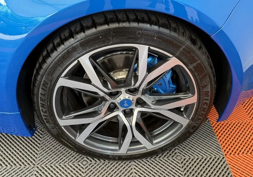 Gros plan sur la roue avant droite bleu métallisé de l'Alpine A110 Legende avec étrier de frein bleu visible.