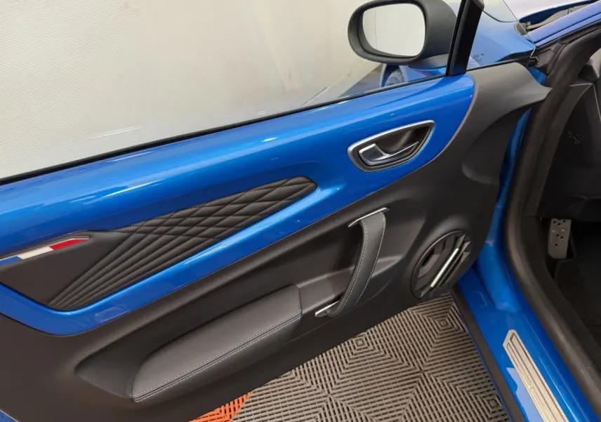 Gros plan sur la porte côté conducteur bleu de l'Alpine A110 Legende 2019 avec surpiqûres et poignée en cuir.