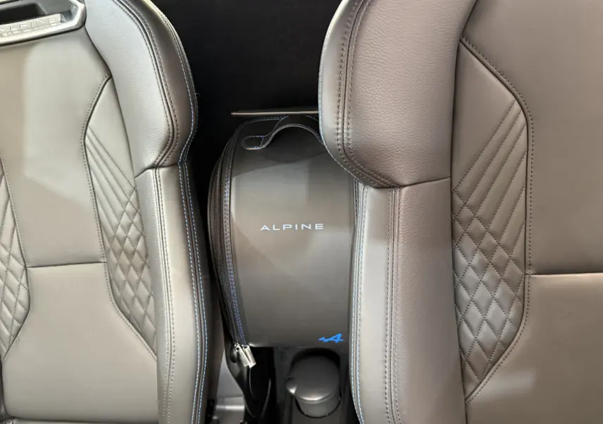 Gros plan sur les sièges en cuir gris avec surpiqûres bleues et sac Alpine entre les sièges de l'Alpine A110 Legende 2019.