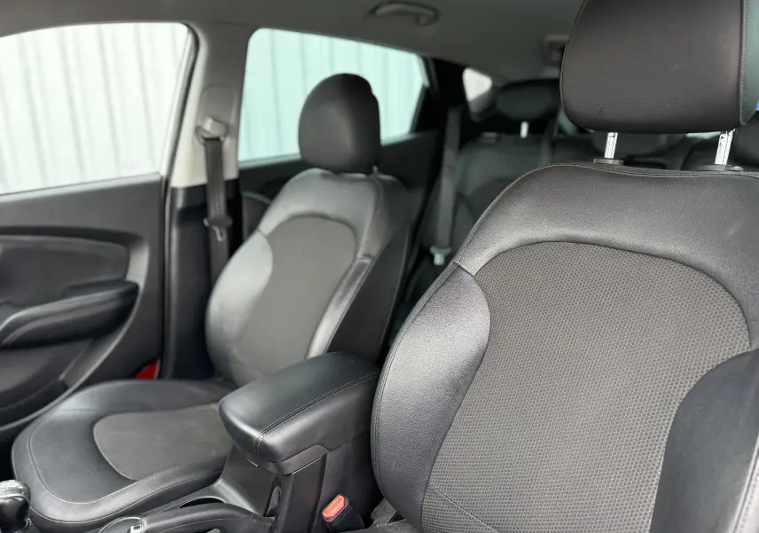 Vue intérieure du côté avant gauche du Hyundai ix35 1.7 CRDI 115 de 2014, sièges en cuir noir et console centrale.