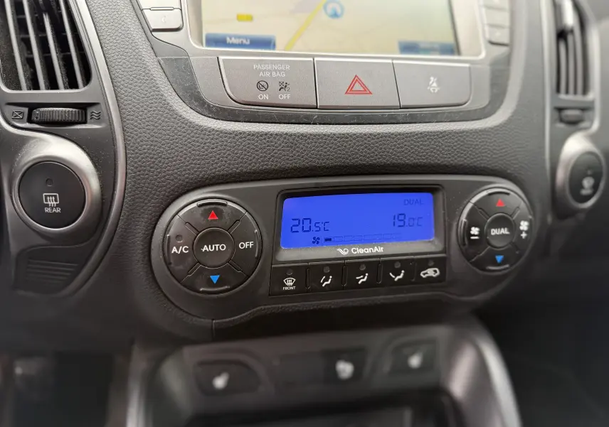 Détail de la console centrale du Hyundai ix35 2014 montrant la climatisation automatique bi-zone avec écran bleu et commandes circulaires.