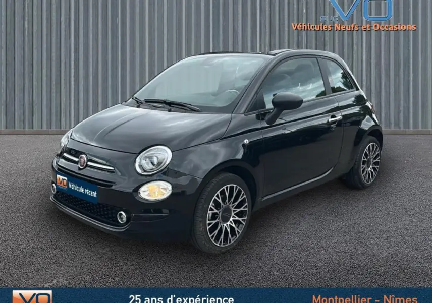 Vue 3/4 avant droite d'une FIAT 500C noire 2024 avec jantes spécifiques et toit ouvrant partiellement visible.