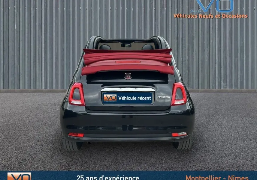 Vue arrière d'une FIAT 500C noire 2024 avec toit rouge décapoté, mettant en valeur la version hybride et la roue de secours.