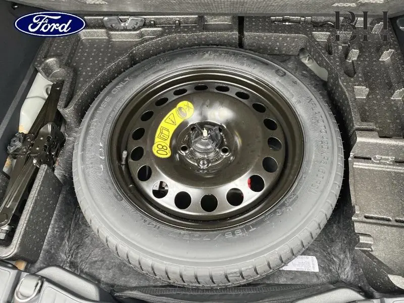 Vue plongeante sur la roue de secours noire dans le coffre du Ford Kuga 2023 gris Magnetic Métallisé.