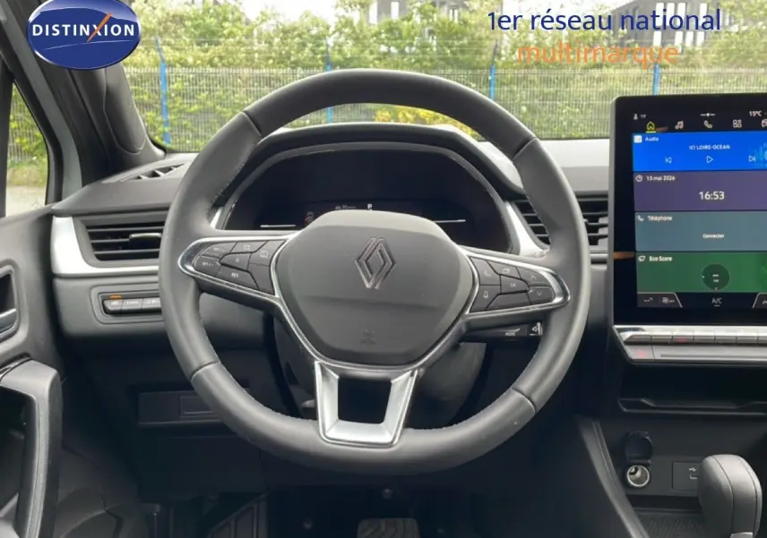 Vue intérieure centrée sur le volant noir Renault avec tableau de bord digital et écran tactile couleur à droite.