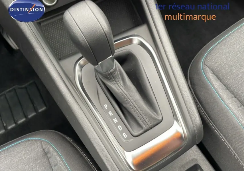Le levier de vitesses automatique noir de la Renault Symbioz E-Tech, entouré de sièges en tissu gris avec surpiqûres bleues.