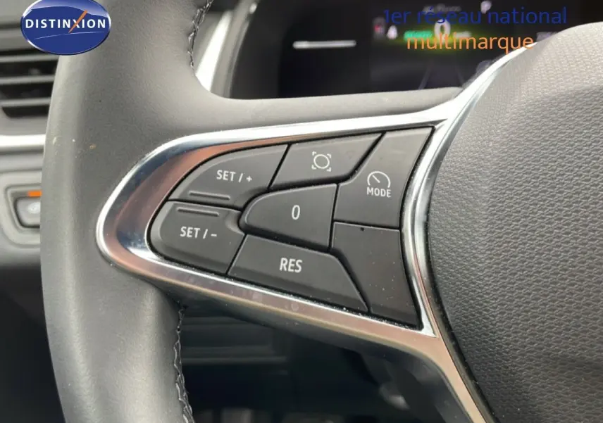Gros plan sur les commandes au volant à gauche du Renault Symbioz blanc nacré, boutons de régulateur de vitesse visibles.