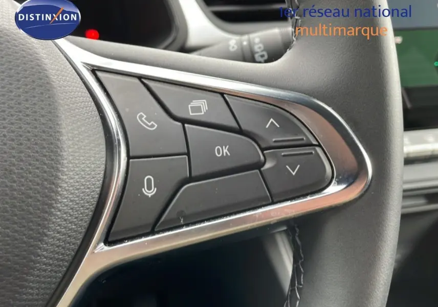 Gros plan sur les commandes au volant côté gauche du Renault Symbioz blanc nacré, avec boutons multifonctions et finition chromée.