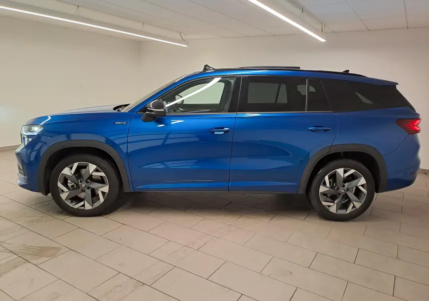 Vue de profil côté gauche d’un Skoda Kodiaq 2025 Bleu RS avec toit panoramique et jantes alliage sport.