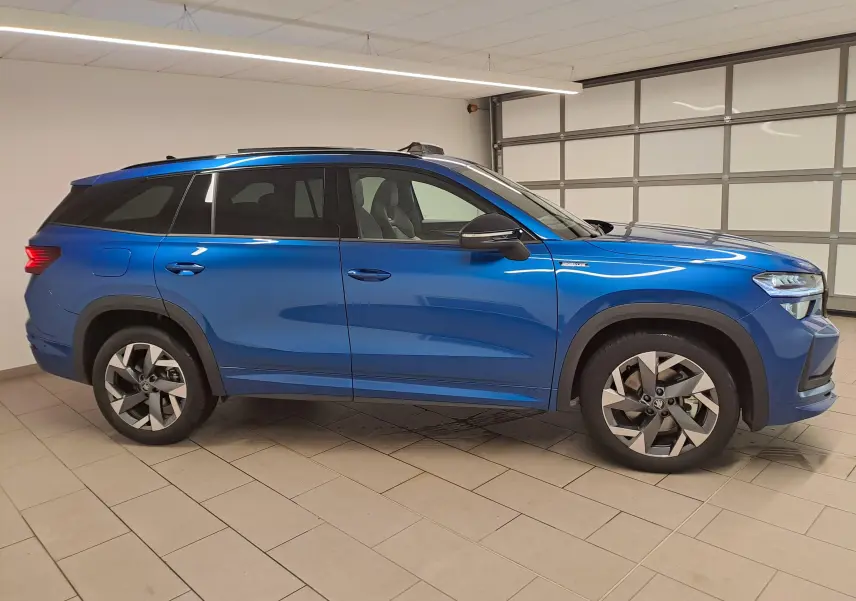 Vue de profil côté gauche d'un Skoda Kodiaq 2025 Bleu RS avec toit panoramique et jantes alliage sport.