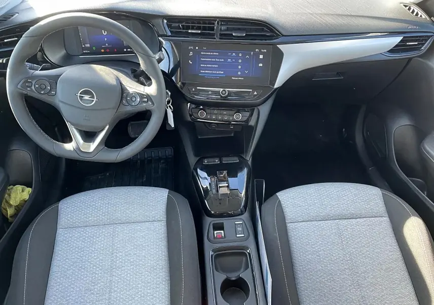 Vue intérieure avant de l’Opel Corsa 2025, tableau de bord noir avec écran tactile et sièges tissu gris clair et noir.