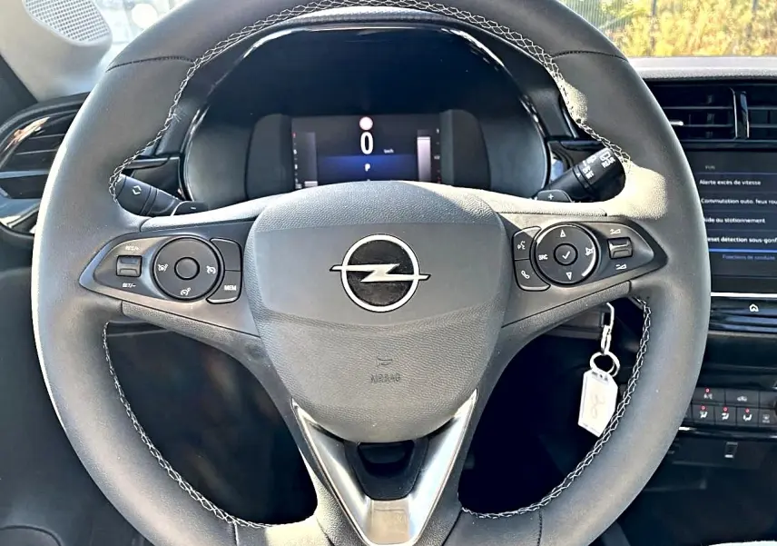Vue frontale du volant sport noir avec surpiqûres blanches de l'Opel Corsa 1.2 turbo 100 edition 2025, tableau de bord en arrière-plan.