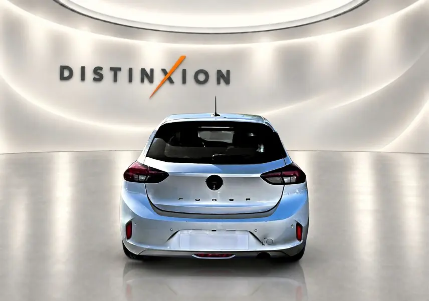 Vue arrière d'une Opel Corsa gris clair 2025 dans un showroom avec logo Distinxion en arrière-plan.