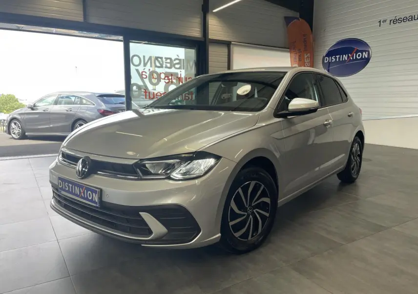 Volkswagen Polo gris clair vue 3/4 avant droit en intérieur avec jantes alliage et calandre chromée.