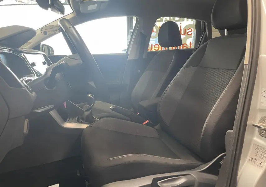 Vue intérieure côté conducteur de la Volkswagen Polo gris clair 2024 avec sièges tissu noirs et volant multifonction.