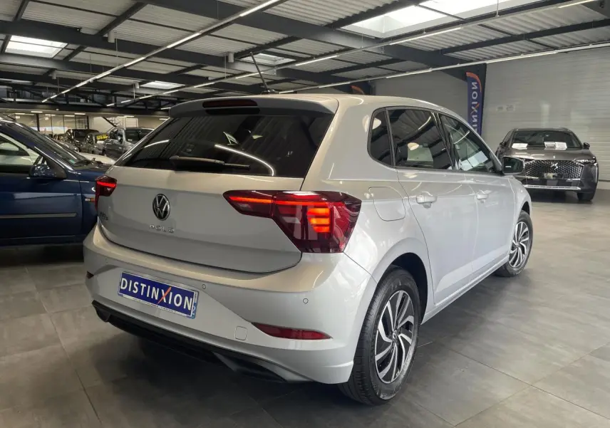 Volkswagen Polo gris clair vue 3/4 arrière droit en intérieur avec vitres arrière surteintées.