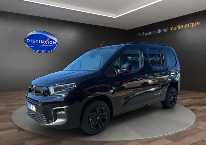 Citroën Berlingo noir en 3/4 avant droit, avec jantes noires et vitres latérales teintées, en intérieur showroom.