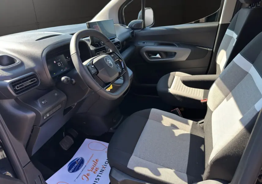 Intérieur avant droit du Citroën Berlingo noir 2026, avec tableau de bord moderne et sièges bicolores gris et noir.
