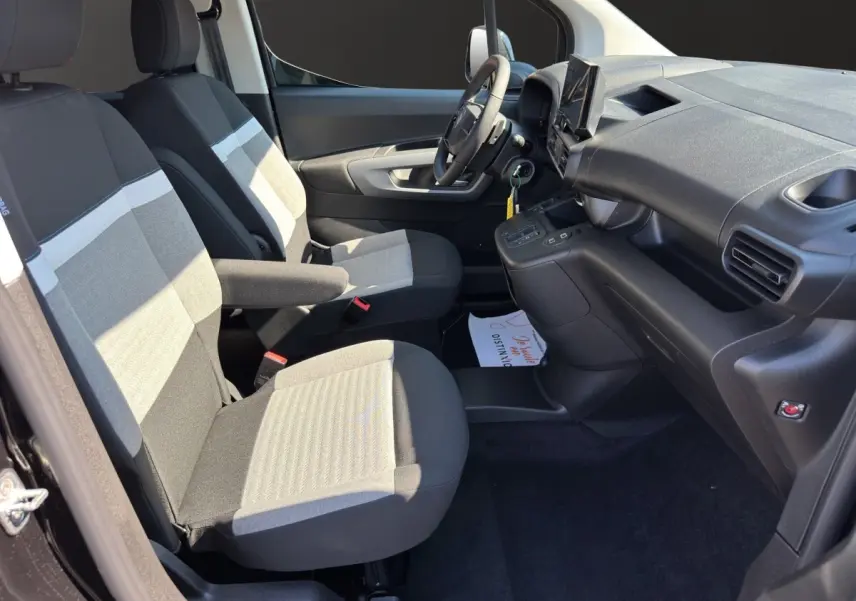 Vue intérieure côté conducteur du Citroën Berlingo 2026, sièges tissu gris et tableau de bord noir avec écran tactile.