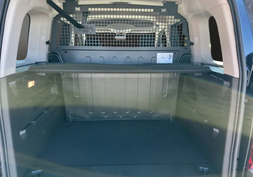 Vue intérieure du coffre noir du Citroën Berlingo 2026 avec séparation métallique et tablette de rangement.