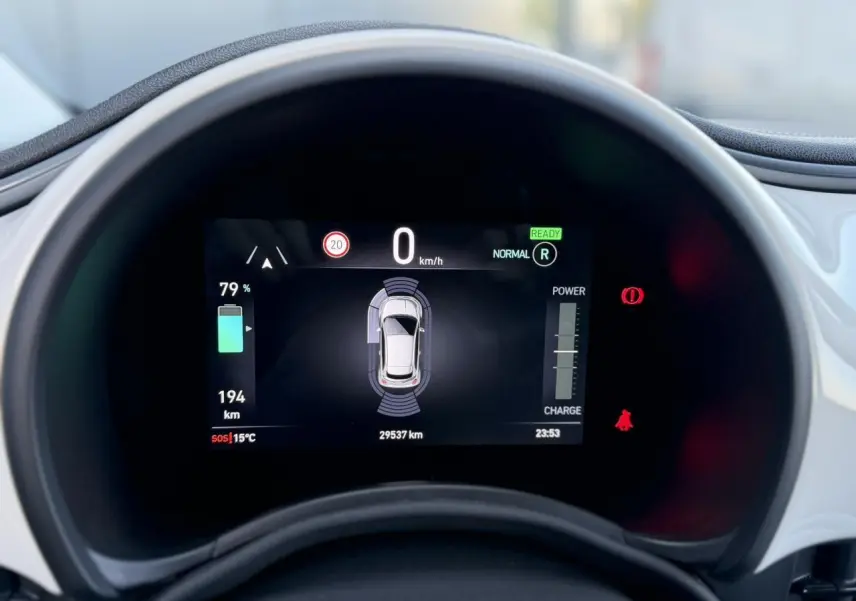 Gros plan sur l'instrumentation numérique de la Fiat 500 électrique blanche, affichant l'autonomie et les alertes.