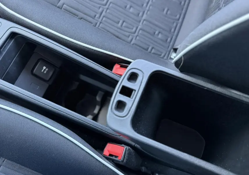Gros plan sur la console centrale ouverte avec accoudoir et sellerie tissu noir du Fiat 500 électrique blanc Arctic.