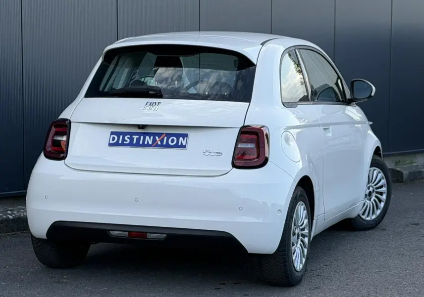 Vue 3/4 arrière droite d'une Fiat 500 électrique blanc Artic avec feux arrière foncés et jantes alliage multibranches.