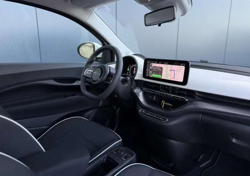 Vue intérieure côté conducteur de la Fiat 500 électrique 2024 avec tableau de bord blanc Artic et écran tactile central.