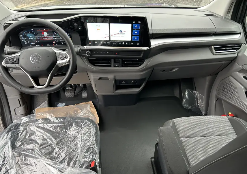 Vue intérieure avant du Volkswagen Transporter T7 ProCab 2026, tableau de bord moderne avec écran tactile et volant multifonction.