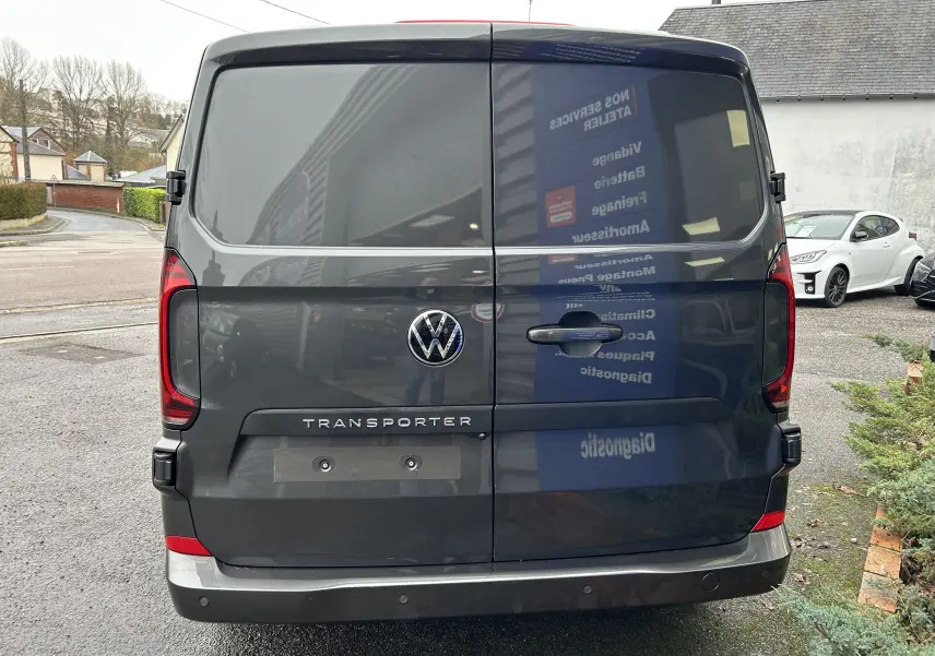 Vue arrière d'un Volkswagen Transporter T7 ProCab graphite dust avec logo VW et feux arrière rouges.