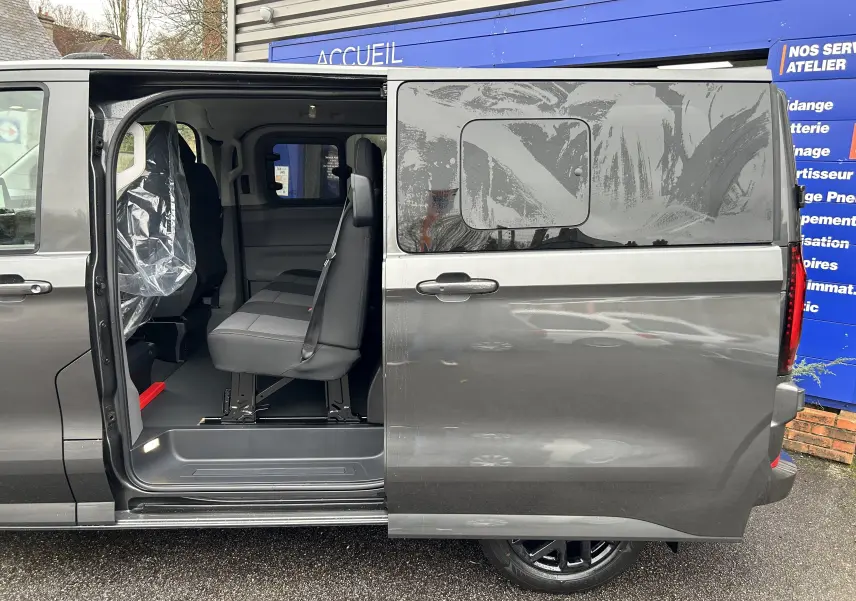 Vue latérale droite d’un Volkswagen Transporter T7 ProCab graphite Dust avec porte coulissante ouverte montrant les sièges cabine.