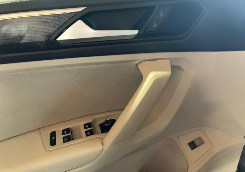 Détail de la porte côté conducteur du Volkswagen Tiguan 2023, avec commandes électriques et finition beige.