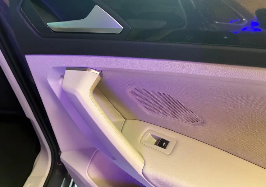 Gros plan sur la poignée de porte intérieure beige et noire du Volkswagen Tiguan 2023, côté gauche.