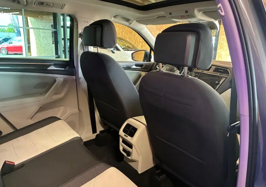 Vue intérieure arrière du Volkswagen Tiguan 2023, sièges bicolores noirs et beige avec toit ouvrant panoramique visible.