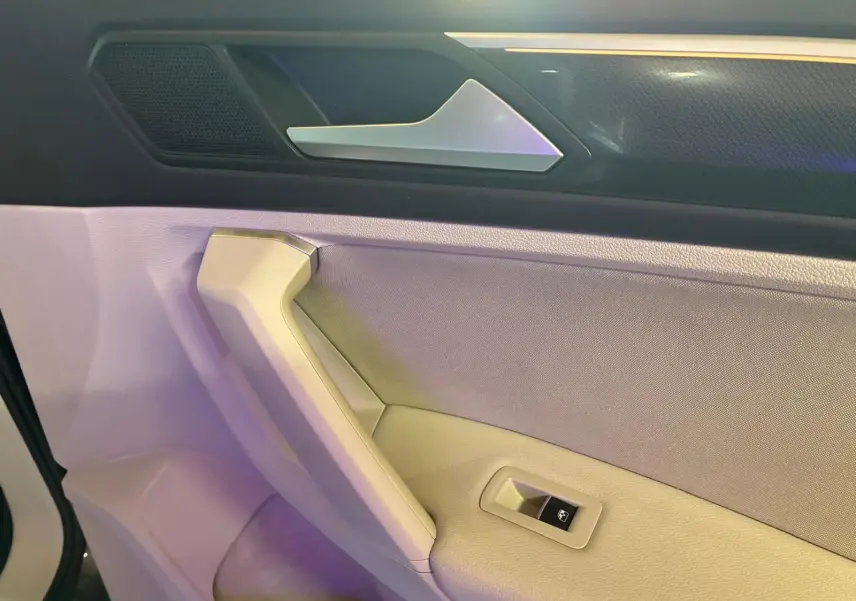 Détail de la poignée intérieure et commande de vitre côté conducteur du Volkswagen Tiguan 2023 gris.