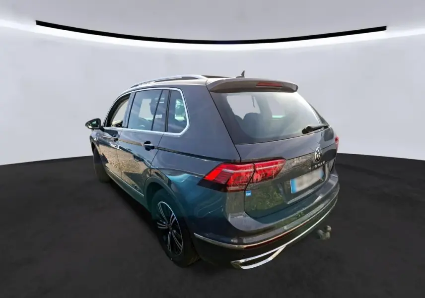 Volkswagen Tiguan gris 2023 vu en 3/4 arrière droit avec toit ouvrant et attelage visible.