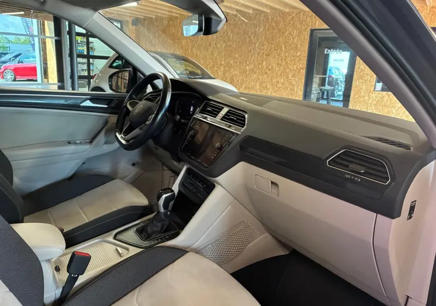 Vue intérieure côté passager avant du Volkswagen Tiguan 2.0 TDI gris, montrant tableau de bord et console centrale.