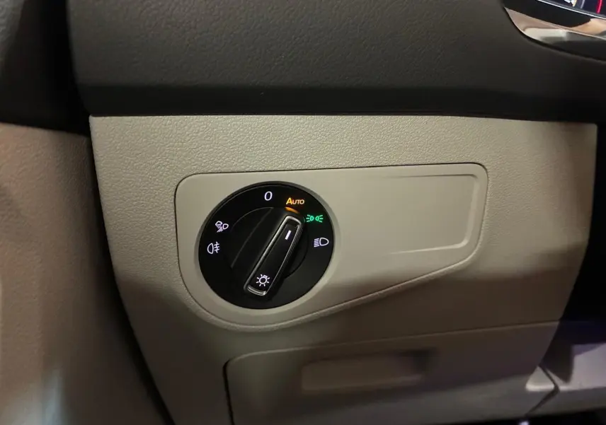Gros plan sur le bouton de commande des phares dans l'habitacle beige du Volkswagen Tiguan 2023 gris.