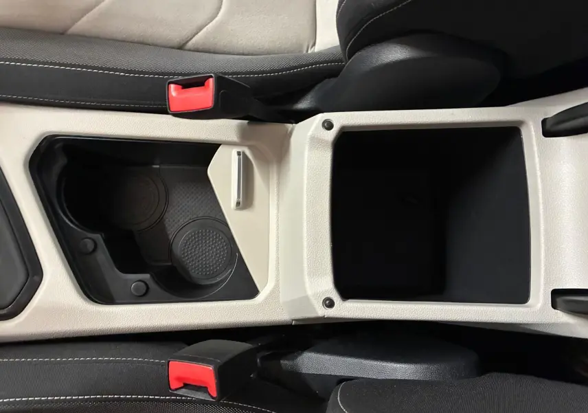 Vue plongeante sur la console centrale beige et noire du Volkswagen Tiguan 2.0 TDI 150 Elegance avec porte-gobelets et accoudoirs.
